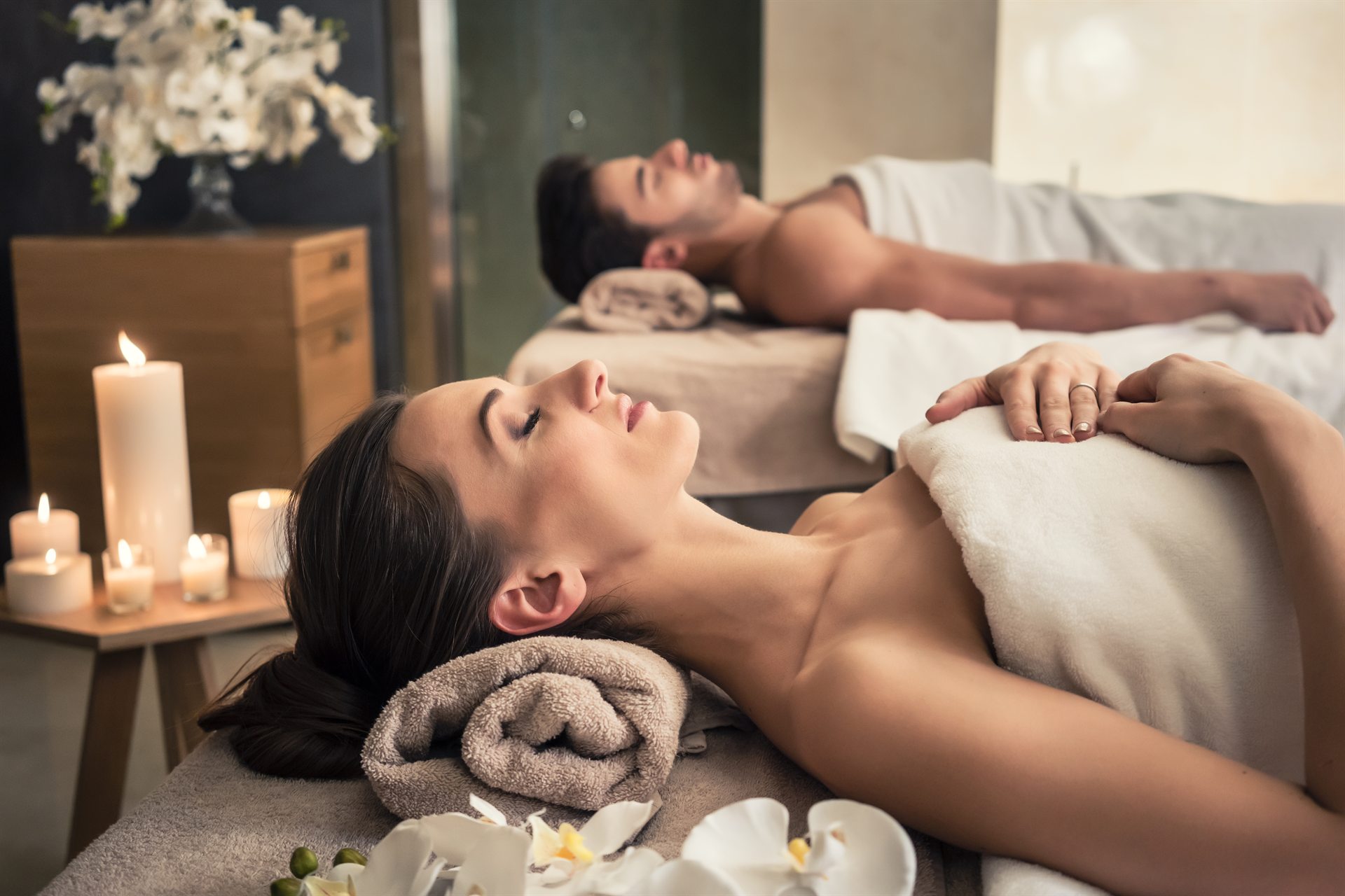 Dwie osoby podczas relaksującego masażu w spa, w otoczeniu świec i ręczników