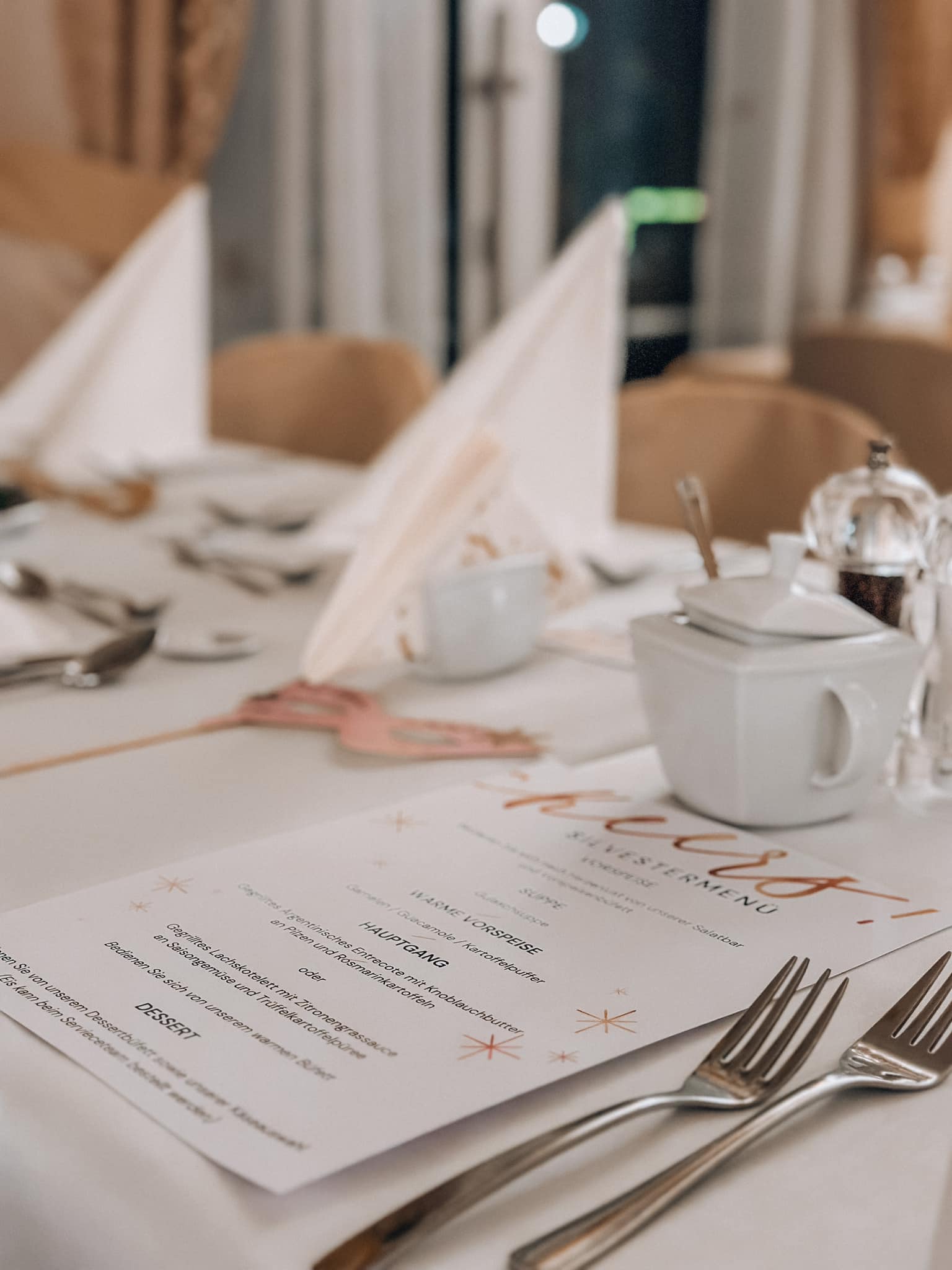 Elegancko nakryty stół z menu, sztućcami i złożonymi serwetkami w ciepłych, jasnych barwach
